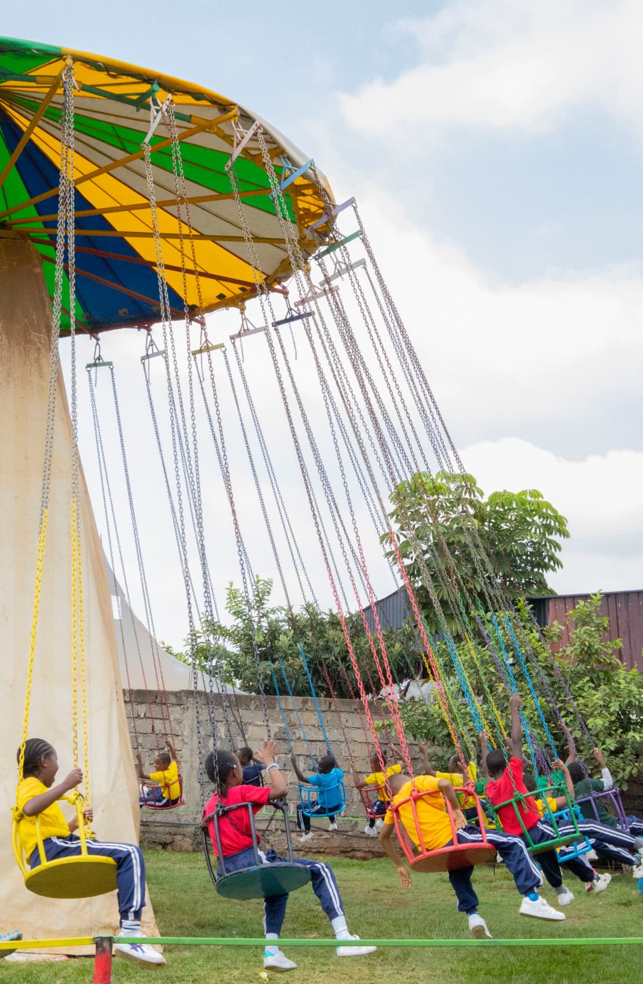 A wide view of school children photographed from behind on the colourful swing ride