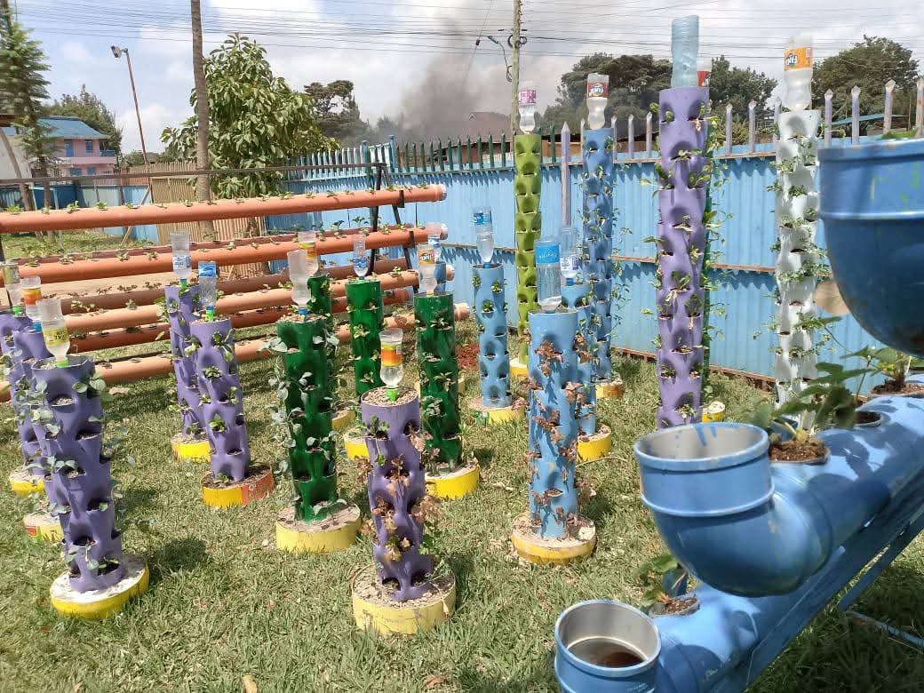 Vertical hydroponic growing towers made from recycled containers, planted with seedlings on the grass