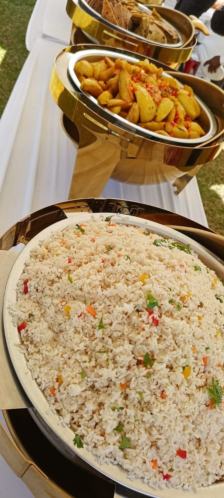 Pilau-style rice and seasoned potato wedges in warming dishes on a buffet table at Vipe Fun Park