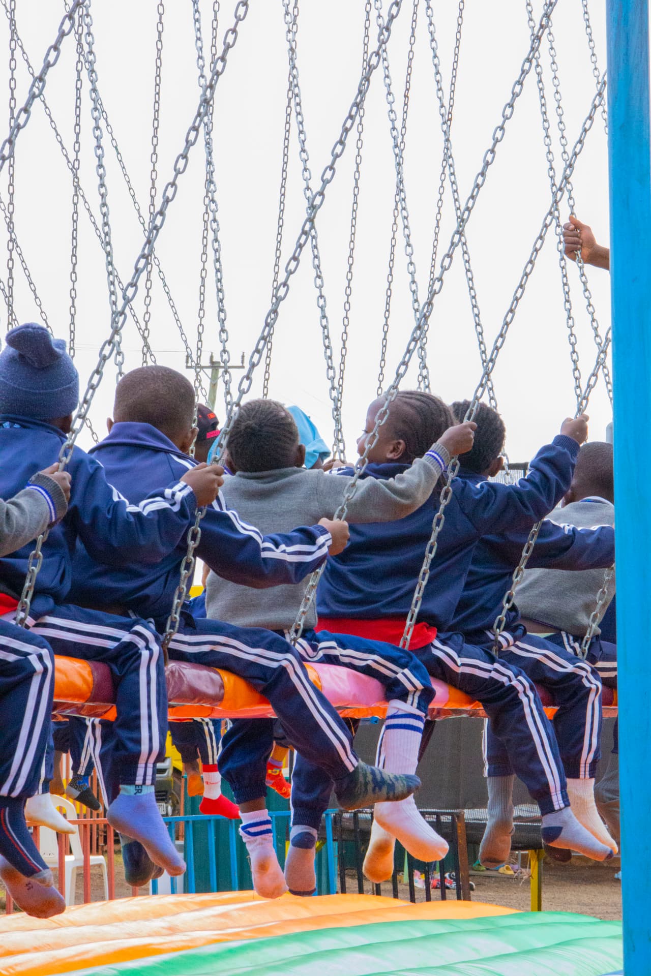 A school group photographed from behind while seated together on the swing ride