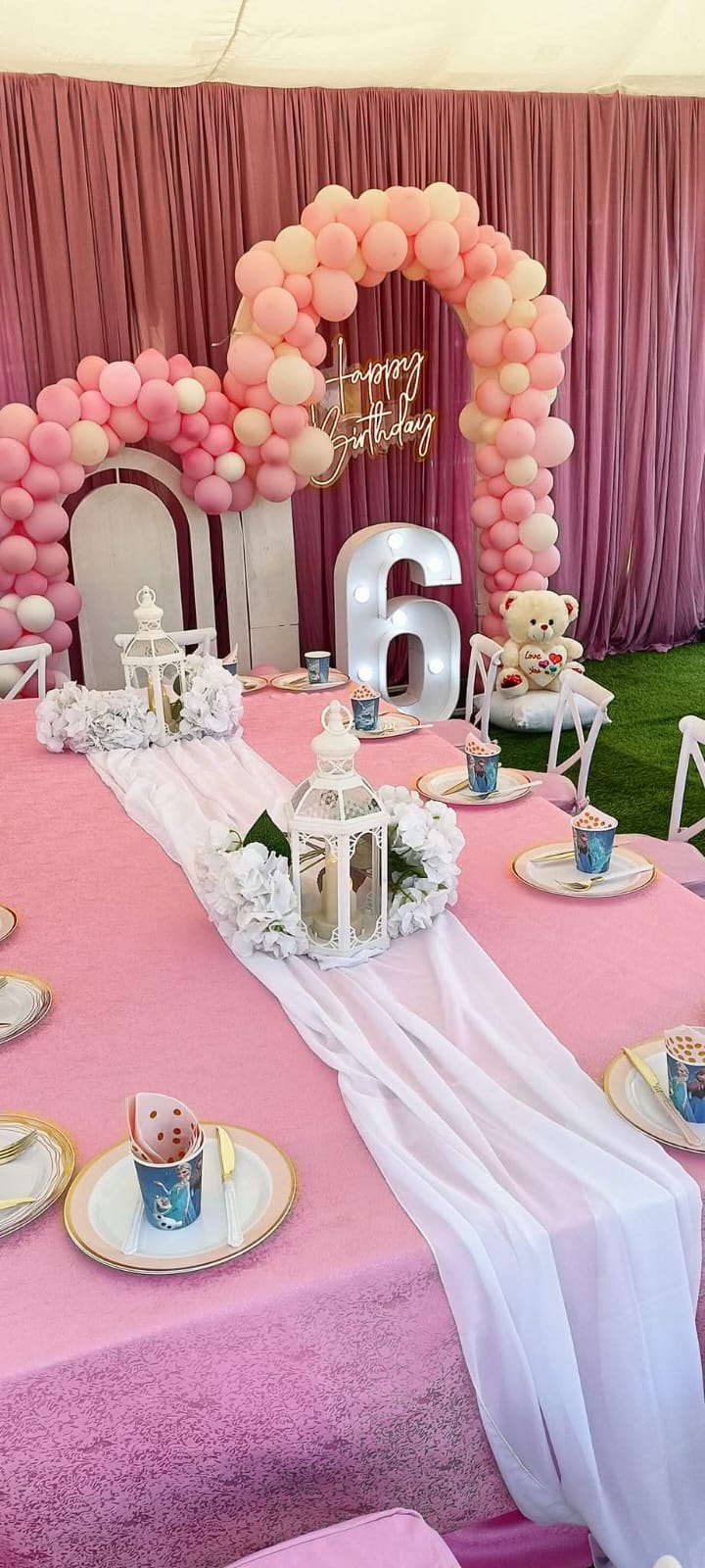A pink birthday table with lanterns, flowers and a balloon arch at Vipe Fun Park