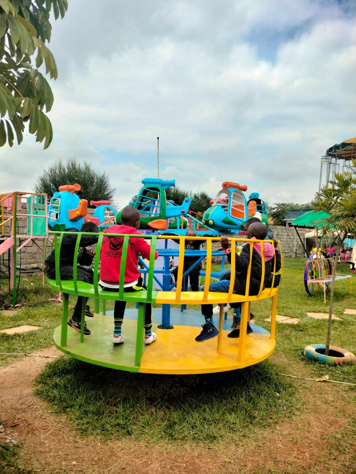 Children riding the colourful helicopter roundabout at Vipe Fun Park, seen from behind