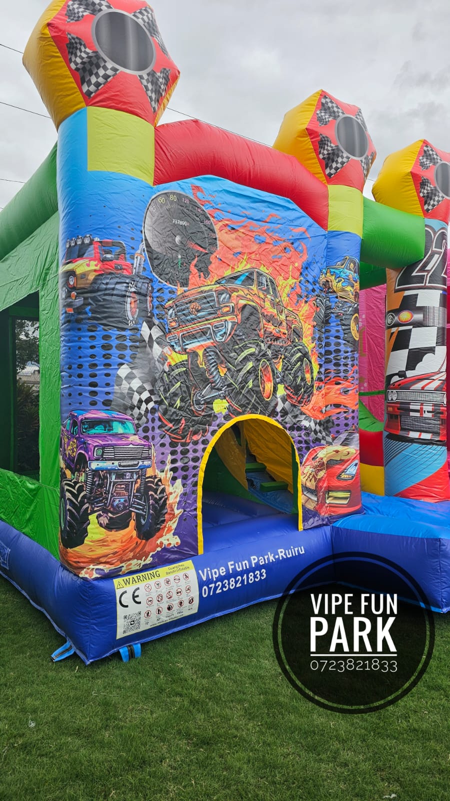 A colourful monster-truck-themed bouncing castle with a small entrance on the lawn